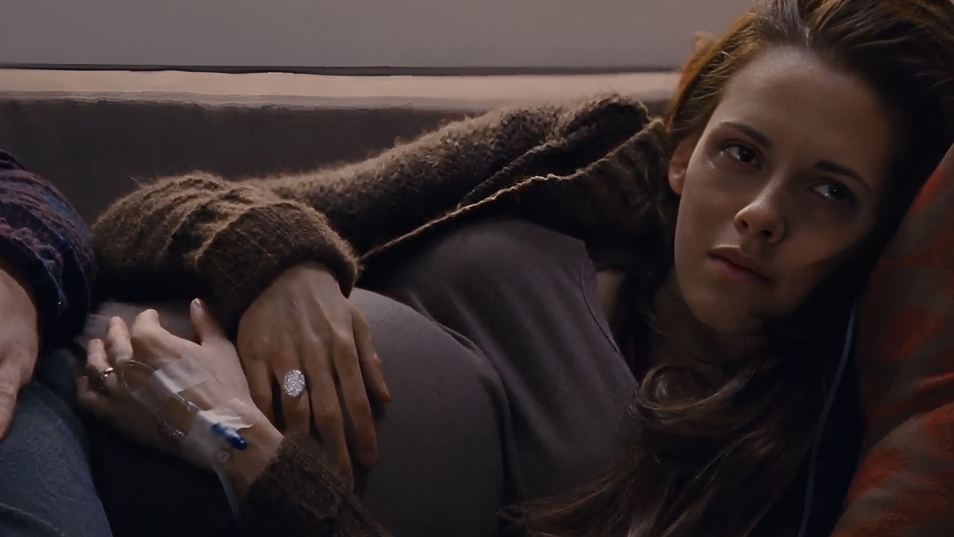 “Weak and worn from the pregnancy, Bella lies on the couch as her unborn child drains her life. (Image via AppleTV)